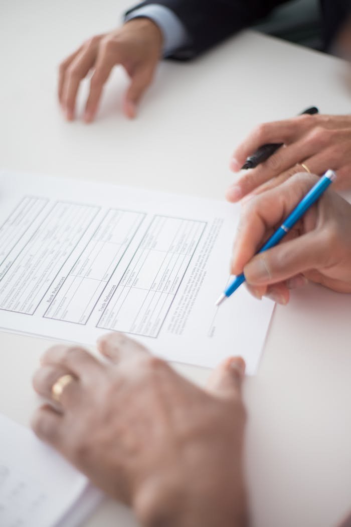 Home Close-up of hands signing a business document on a white surface with a pen.